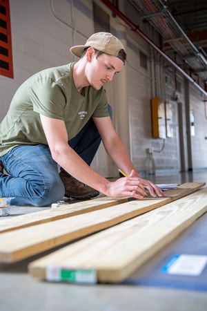 Student measuring wood to cut.